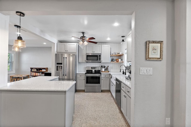 kitchen featuring sink, hanging light fixtures, stainless steel appliances, tasteful backsplash, and light stone countertops