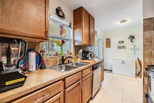 kitchen featuring appliances with stainless steel finishes, sink, backsplash, light tile patterned floors, and a textured ceiling