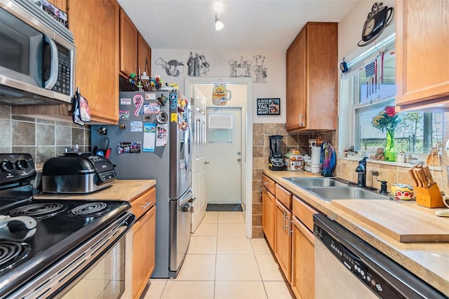 kitchen featuring tasteful backsplash, appliances with stainless steel finishes, sink, and light tile patterned floors