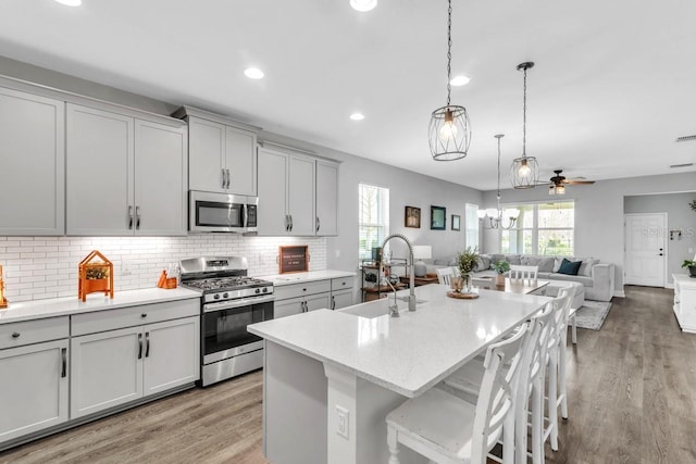 kitchen featuring a breakfast bar, sink, stainless steel appliances, a kitchen island with sink, and backsplash