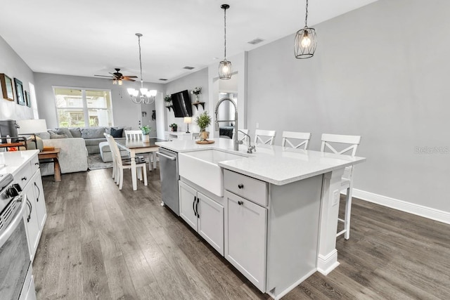 kitchen featuring a breakfast bar, an island with sink, sink, white cabinets, and hanging light fixtures