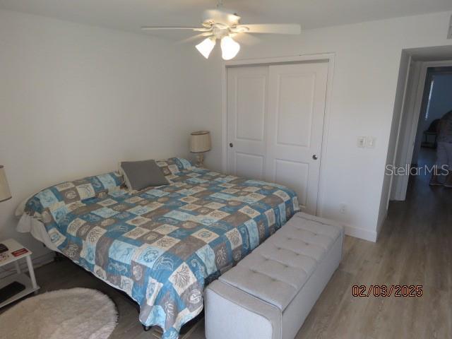 bedroom with hardwood / wood-style flooring, ceiling fan, and a closet