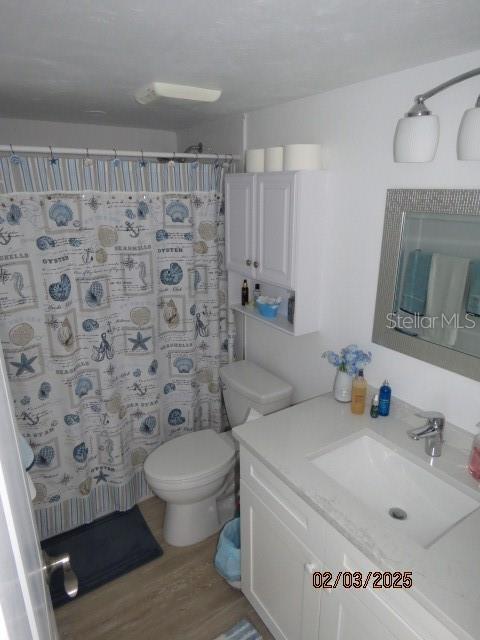 bathroom with a shower with curtain, vanity, hardwood / wood-style floors, and toilet