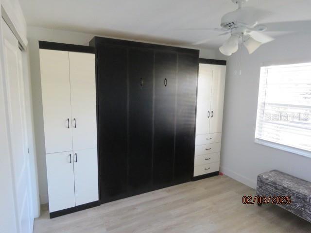 unfurnished bedroom featuring ceiling fan, light hardwood / wood-style floors, and multiple closets