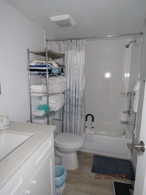 full bathroom featuring toilet, vanity, shower / bathtub combination with curtain, and hardwood / wood-style floors