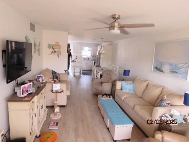 living room with light hardwood / wood-style flooring and ceiling fan