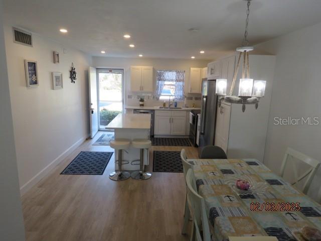 dining room with sink, a chandelier, and light hardwood / wood-style flooring