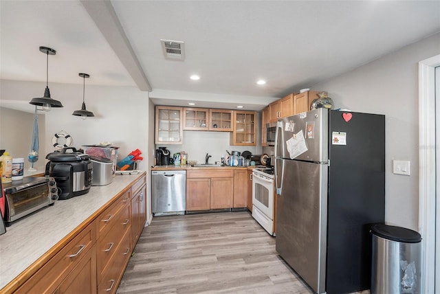 kitchen featuring pendant lighting, sink, stainless steel appliances, and light wood-type flooring