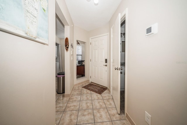 corridor featuring light tile patterned floors and baseboards