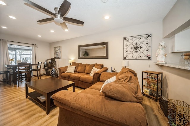 living area with light wood-type flooring, ceiling fan, and recessed lighting