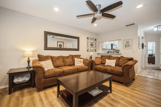 living room with light wood-style floors, baseboards, visible vents, and recessed lighting