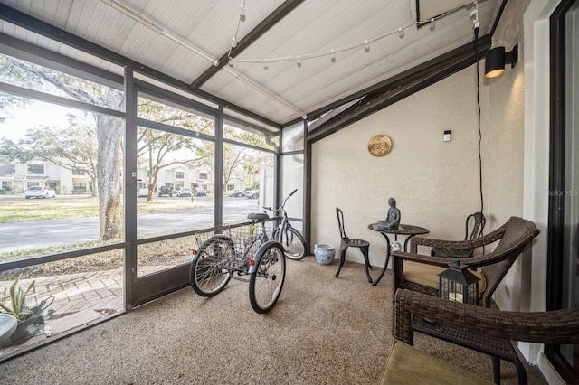 sunroom / solarium featuring a residential view, vaulted ceiling, and plenty of natural light