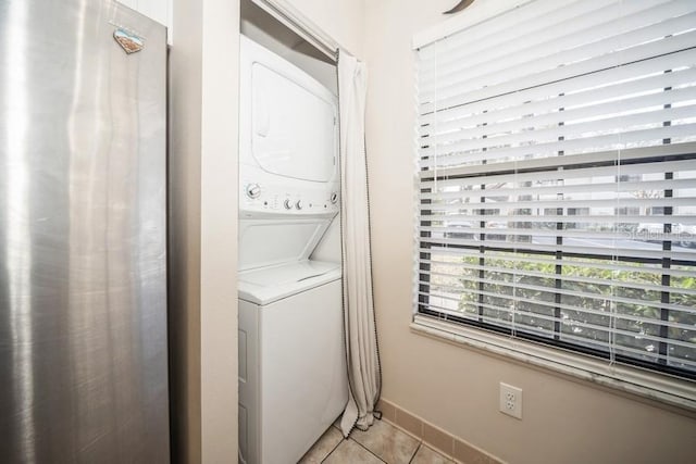 laundry area with laundry area, baseboards, stacked washer / drying machine, and light tile patterned flooring