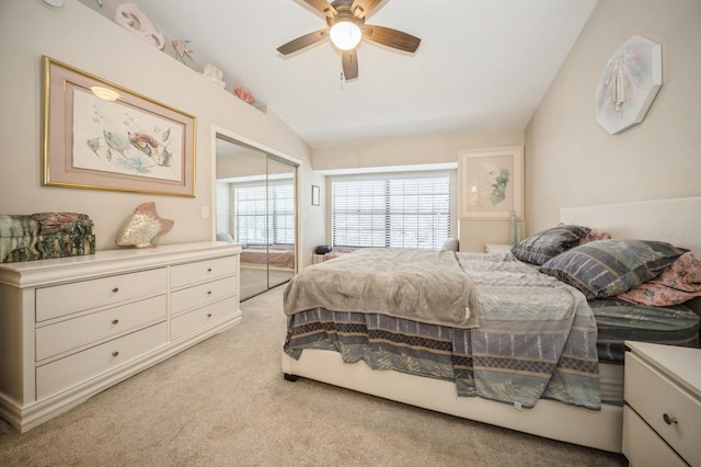 bedroom featuring lofted ceiling, a closet, a ceiling fan, and light colored carpet