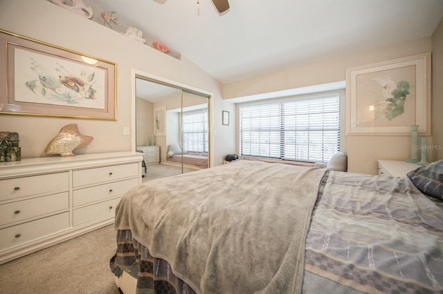 bedroom with a ceiling fan, lofted ceiling, a closet, and light carpet