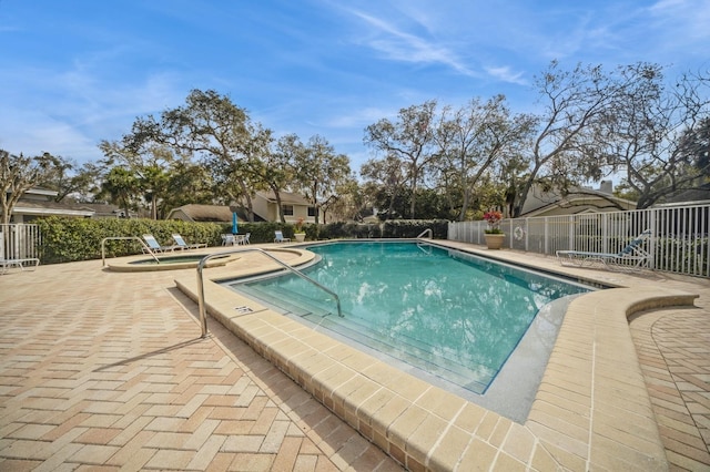 community pool with a patio area and fence