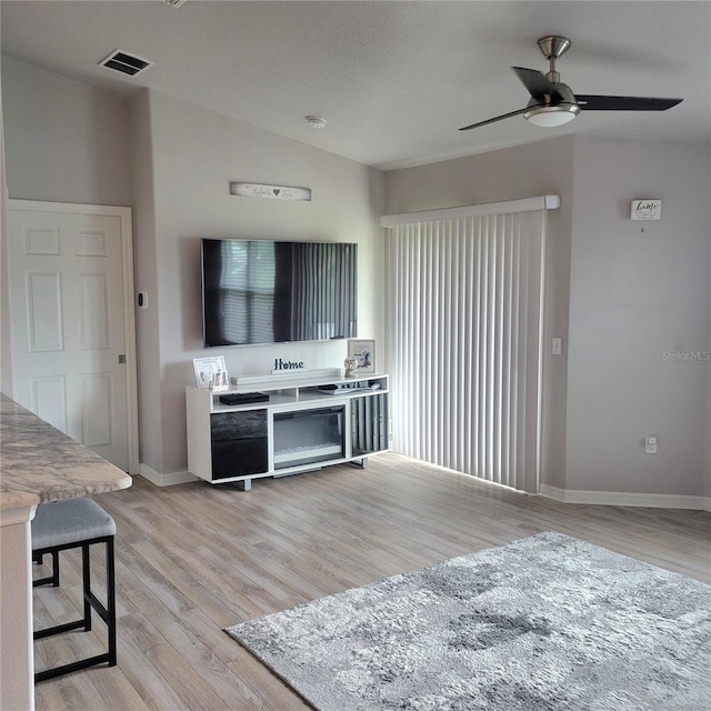 living room featuring ceiling fan, lofted ceiling, and light wood-type flooring