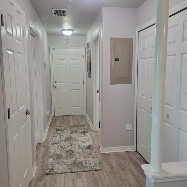 hallway featuring a textured ceiling, electric panel, and light hardwood / wood-style floors