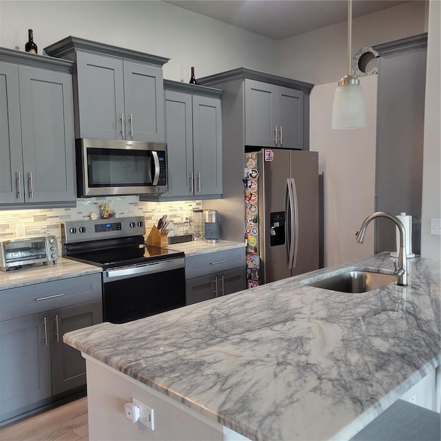 kitchen with sink, gray cabinets, pendant lighting, stainless steel appliances, and decorative backsplash