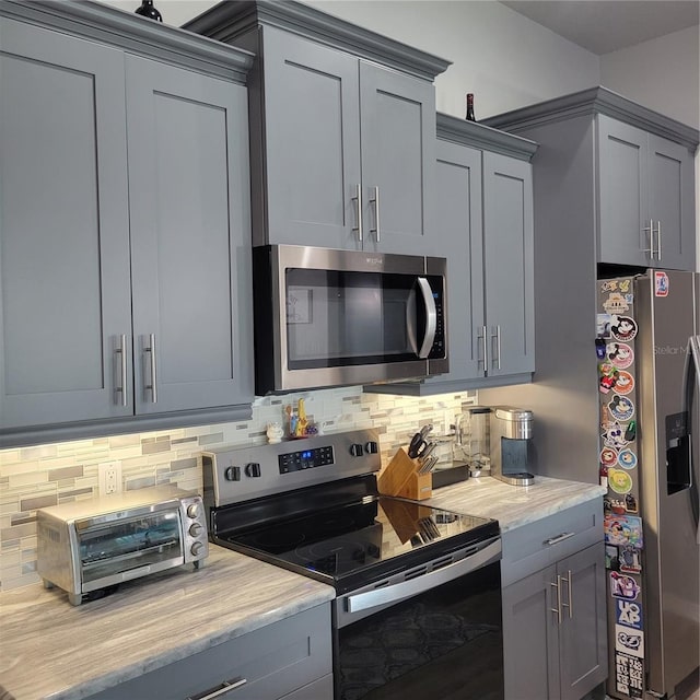 kitchen featuring decorative backsplash, gray cabinets, and appliances with stainless steel finishes