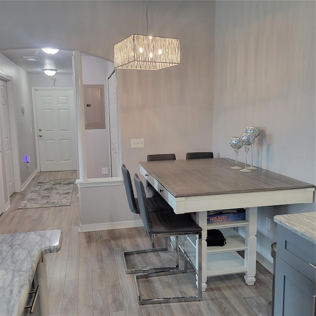 dining space featuring electric panel, a chandelier, and light hardwood / wood-style flooring