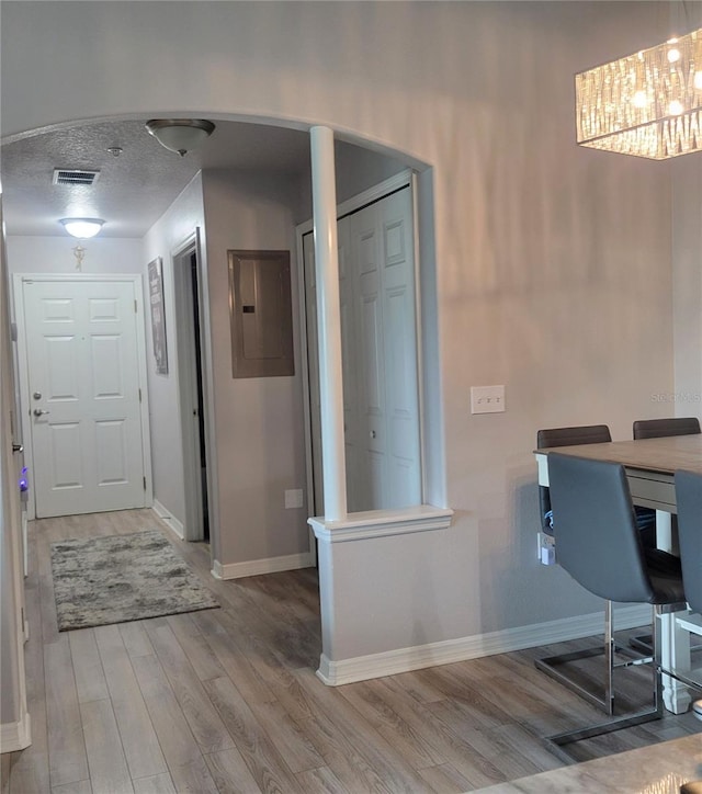 unfurnished office featuring hardwood / wood-style flooring, electric panel, and a textured ceiling