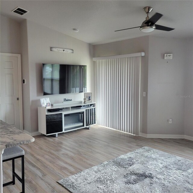 living room featuring lofted ceiling, light hardwood / wood-style floors, and ceiling fan