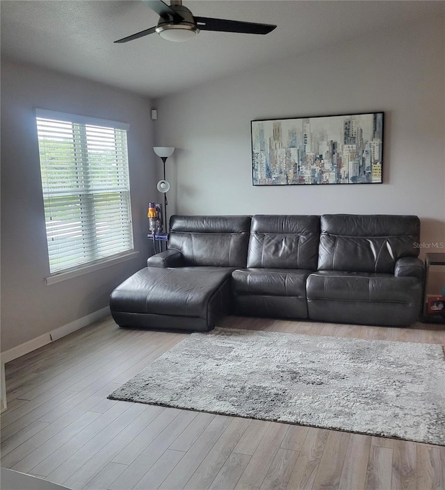 living room featuring ceiling fan, light hardwood / wood-style floors, and vaulted ceiling