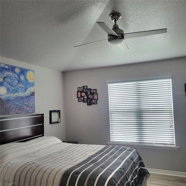 bedroom featuring multiple windows, hardwood / wood-style flooring, a textured ceiling, and ceiling fan