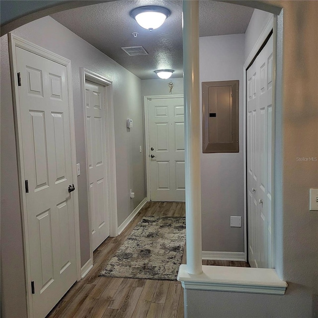 hall with wood-type flooring, electric panel, and a textured ceiling