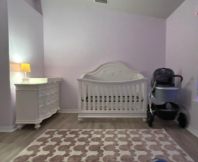 bedroom with a crib and wood-type flooring