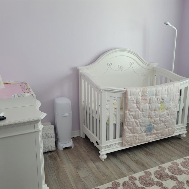 bedroom with hardwood / wood-style flooring and a crib