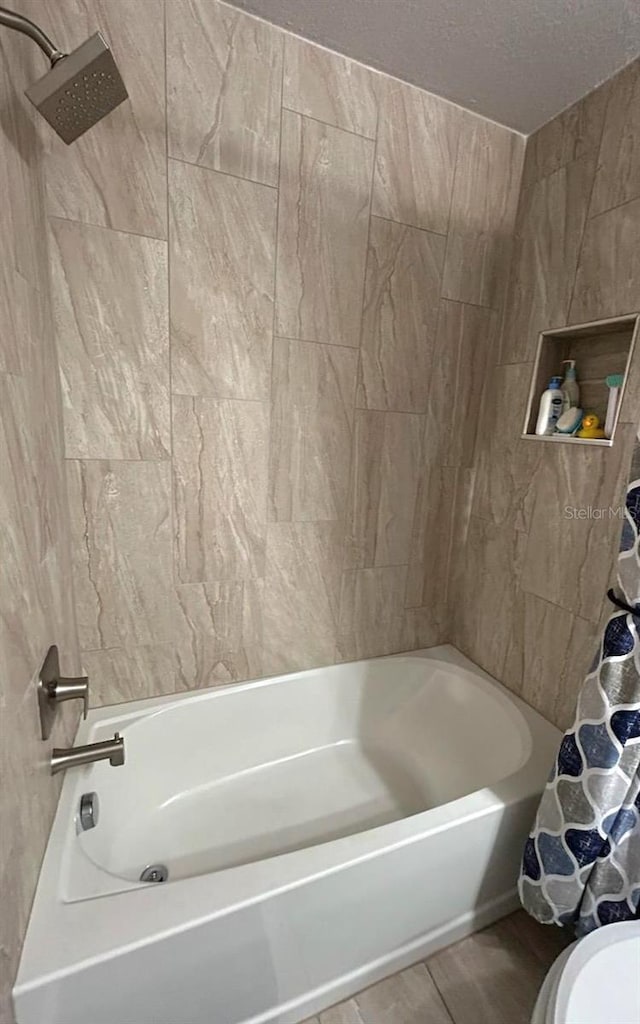 bathroom featuring shower / tub combo with curtain, a textured ceiling, and toilet