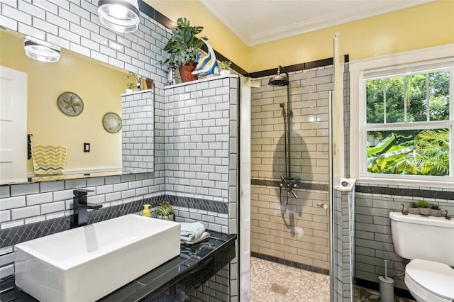 bathroom with sink, tile walls, tiled shower, toilet, and crown molding