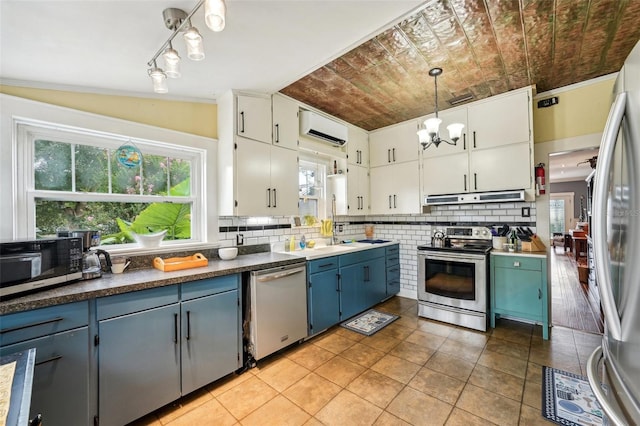 kitchen with white cabinets, decorative backsplash, hanging light fixtures, stainless steel appliances, and a wall unit AC