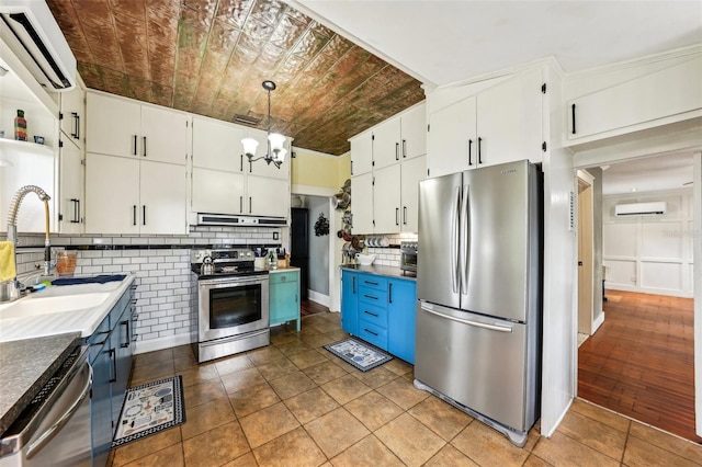 kitchen featuring appliances with stainless steel finishes, sink, white cabinets, and decorative light fixtures