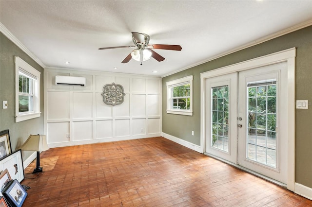 unfurnished room featuring crown molding, a wall mounted AC, hardwood / wood-style floors, and french doors