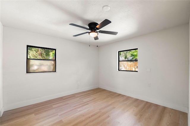 empty room with ceiling fan, a textured ceiling, and light wood-type flooring