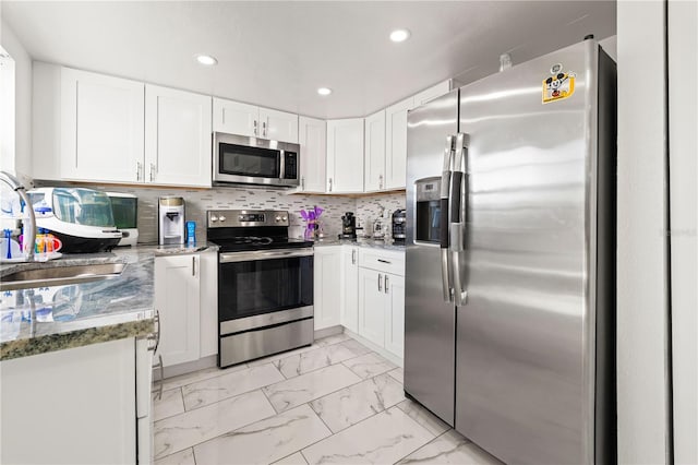 kitchen with appliances with stainless steel finishes, sink, white cabinets, and stone counters