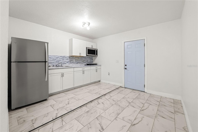 kitchen featuring decorative backsplash, appliances with stainless steel finishes, white cabinetry, and sink