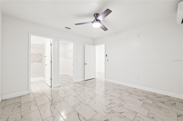 unfurnished bedroom with ensuite bathroom, ceiling fan, a closet, and a walk in closet