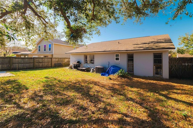 back of property with a yard and central AC unit