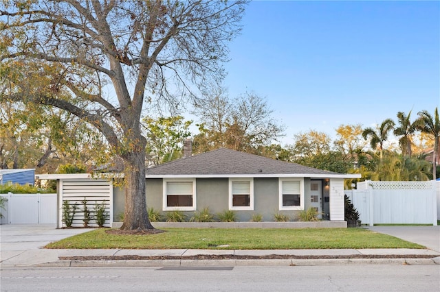 view of front facade featuring a shingled roof, fence, driveway, a gate, and stucco siding