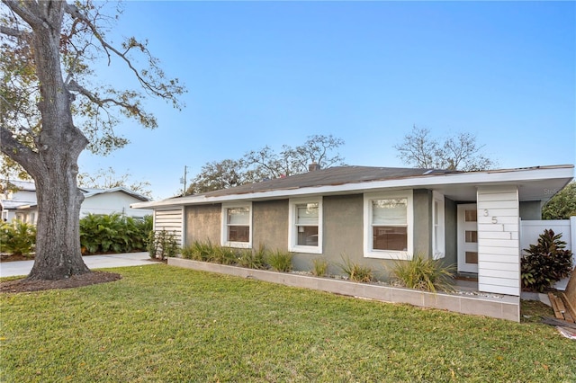 view of front of home with a front yard, driveway, and stucco siding