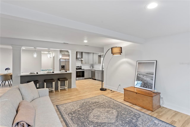 living room with baseboards, recessed lighting, light wood-type flooring, and ornate columns