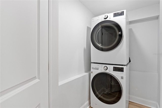 laundry area featuring stacked washer and dryer and light wood-style flooring