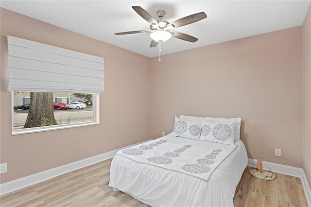 bedroom featuring a ceiling fan, light wood-style flooring, and baseboards