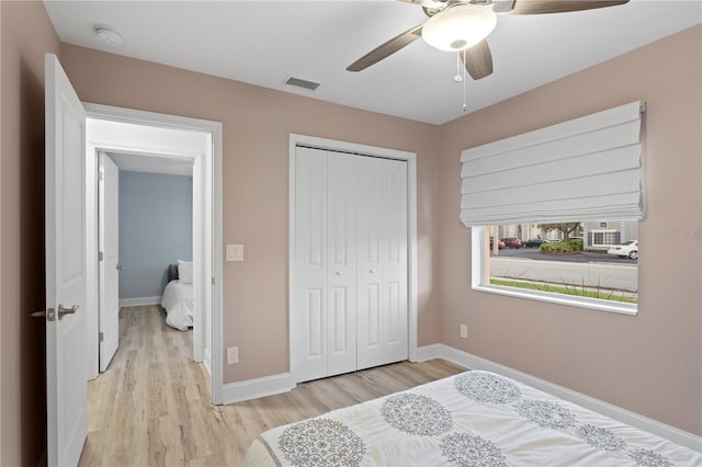 bedroom with a ceiling fan, visible vents, baseboards, a closet, and light wood finished floors