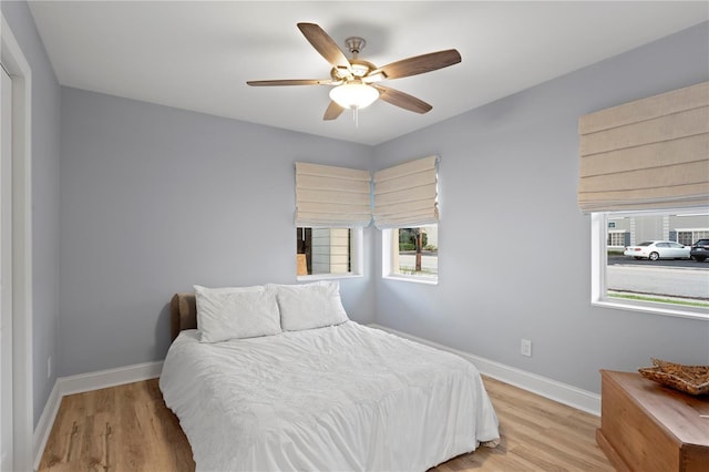 bedroom featuring light wood finished floors, baseboards, and a ceiling fan