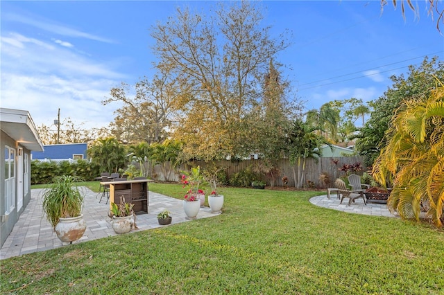 view of yard with a fenced backyard, a patio, a fire pit, and exterior bar